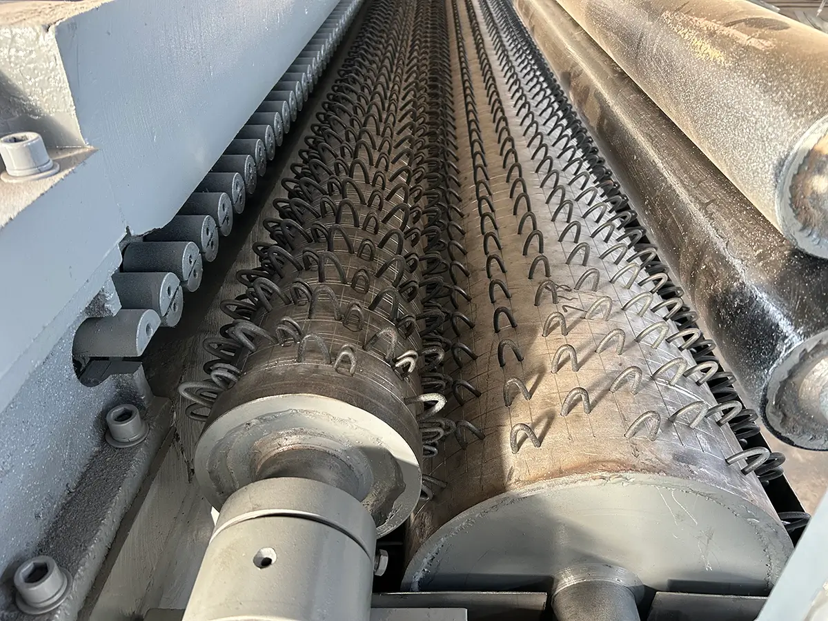 Mesh being pressed flat through calibrated forming rollers and cooled to lock in aperture dimensions and surface uniformity