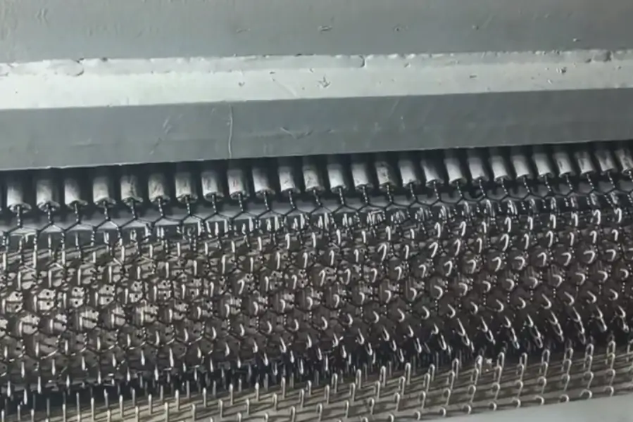 Woven PET mesh passing through a pre-heat zone to soften fibers, set hexagonal geometry, and eliminate residual stress