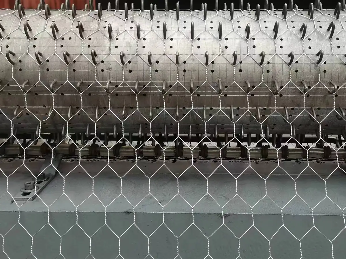 Metal wire being fed into the CNC hexagonal wire mesh machine during the weaving process, forming a uniform hexagonal wire mesh structure