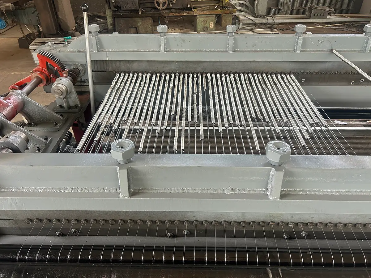 Close-up of coiled steel wires feeding into a hexagonal wire mesh machine